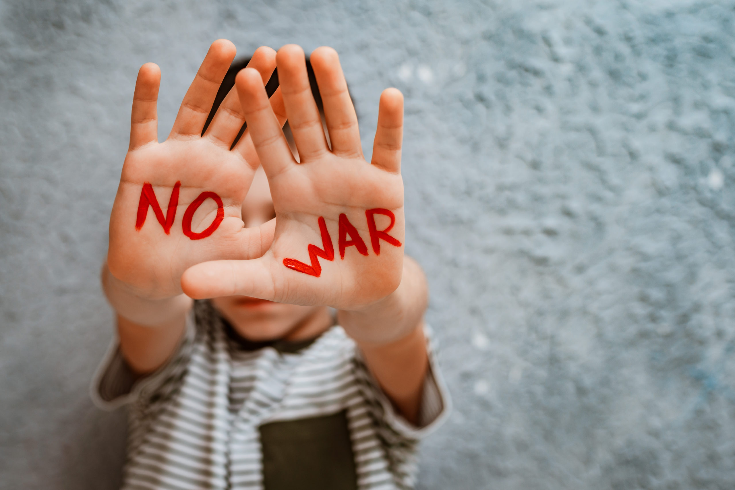 slogan of peace without war is written on the child’s hand in red no war.